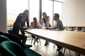 Five multinational workgroup creative team brainstorming thinking gathered in morning briefing group meeting in board room discuss ideas planning future projects solving problems together at workplace