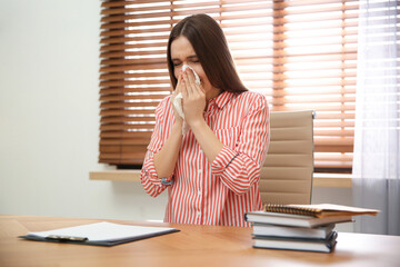 Poster - Sick young woman sneezing at workplace. Influenza virus