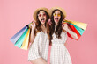 © Drobot Dean - Image of excited women in straw hats holding sopping bags and hugging