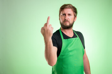 Supermarket employee with green apron and black t-shirt showing fuck you