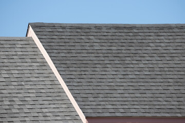 Sticker - Roof shingles on top of the house against blue sky with cloud, dark asphalt tiles on the roof background.