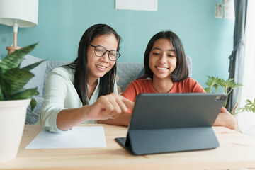 asian family with daughter do homework by using tablet with mother help.