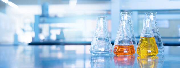 Wall Mural - orange yellow solution in science glass flask win blue chemistry laboratory banner background