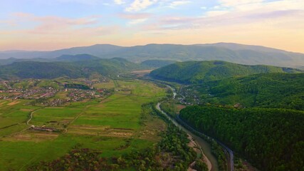 Wall Mural - drone flies above countryside landscape in spring at sunrise small town with bright red roofs mountains with green trees