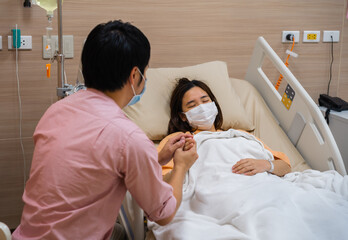 man visiting and take care female patient on bed at hospital. people must be wearing medical mask to prevention coronavirus(covid-19) pandemic.