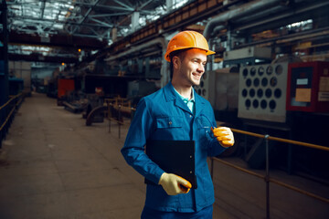 Poster - Smiling worker holds notebook, factory floor