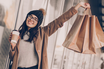 Wall Mural - Beautiful fashionable woman drink coffee walking near mall with shopping bags.