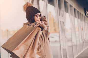 Wall Mural - Beautiful fashionable woman drink coffee walking near mall with shopping bags.