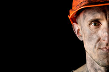 The Face Of A Male Miner In A Helmet On A Black Background. Copy Space.