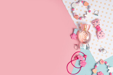 children's flat lay. perfume in the form of candy, children's jewelry and hair accessories on a pink