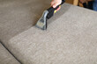 Male housekeeper arm cleaning sofa with washing vacuum cleaner