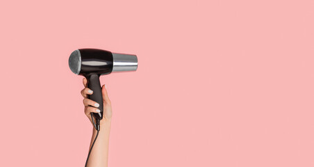 Wall Mural - Closeup view of female hand showing modern hairdryer on pink background, empty space