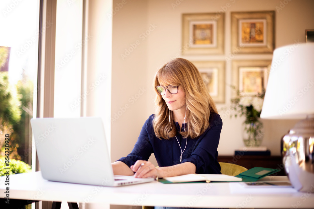 Shot of woman sitting behind her laptop and working from home - obrazy, fototapety, plakaty 
