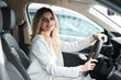 © Andrii  - Young woman driving a car. Elegant business lady driving an expensive car