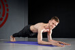 © galilo3981 - Younf athletic man is standing in forearm plank on yoga mat.