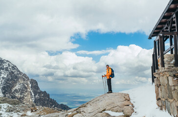 Wall Mural - dressed bright orange jacket backpacker walking in high tatras mountain range, slovakia using trekki