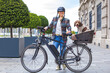 young woman pushing her e-bike with the dog in the basket