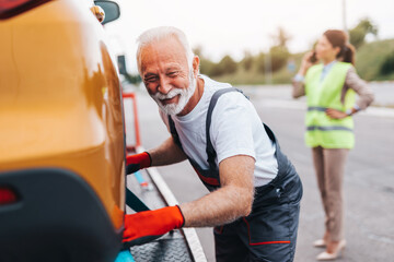 Handsome senior man working in towing service on the road. Roadside assistance concept.