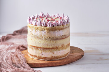 Cake with white chocolate and cherry on a wooden board on a white table. Dessert decorated with homemade marshmallows.