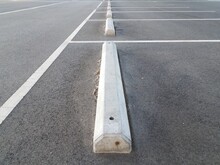 Cement Curb In Parking Lot With Asphalt