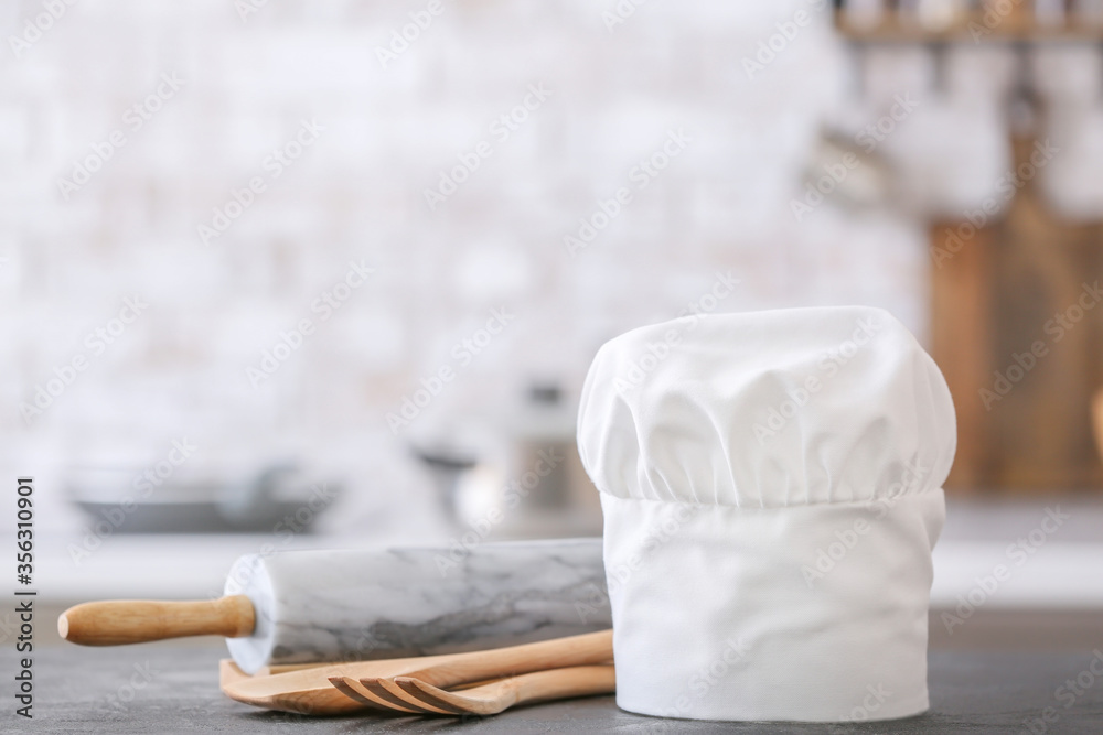 Chef's hat and utensils on table in kitchen