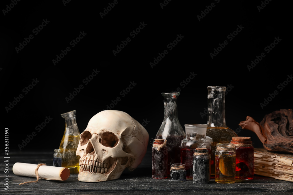 Potions, human skull and old book on alchemist's table