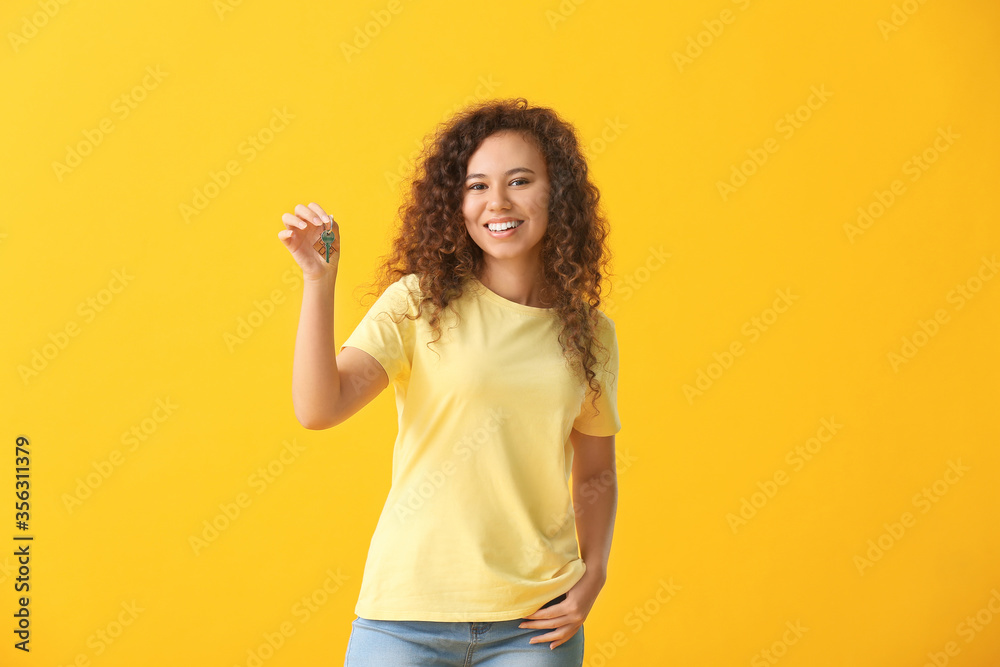 Happy young woman with key on color background