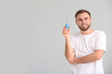 Poster - Young man with car key on grey background