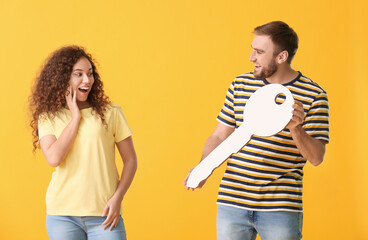 Sticker - Happy young couple with big paper key on color background