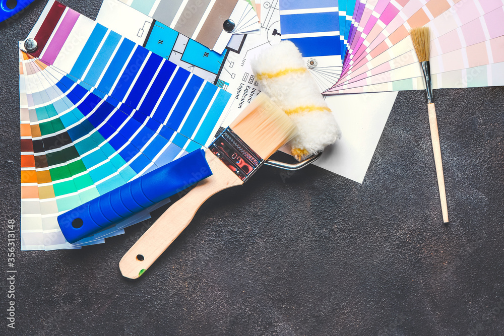 Color palettes with building plan, roller and paint brushes on dark background