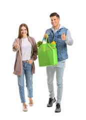 Wall Mural - Couple with food in bag showing thumb-up gesture on white background