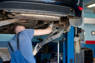 Car service. Mechanic repairing chassis of the car