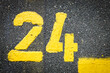 © YK - Number twenty-four yellow painted on the street,asphalt marks on cracked street, space for text, no people