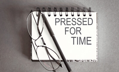 Business concept - Top view notebook writing PRESSED FOR TIME on gray background