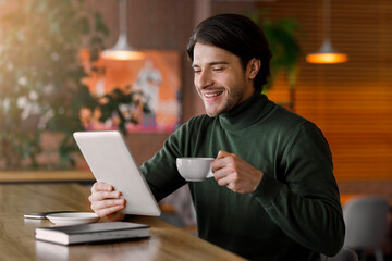 Happy businessman reading emails while drinking coffe at cafe