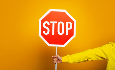 stop sign. girl in a yellow hoodie showing only her hand with 