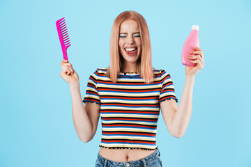 Canvas Print - Image of joyful charming girl holding shampoo and comb while laughing