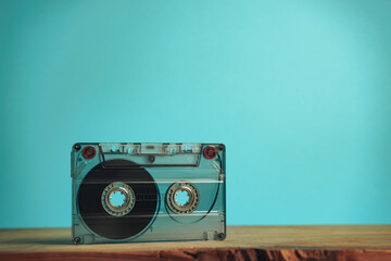 Beautiful Audio cassette tape on a red wooden table and blue space. Minimalism retro style concept. 80s. Background pattern for design.