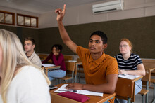 Side View Of Student Raising His Hand In Class