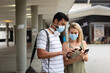© Wavebreak Media - Caucasian couple on the go wearing a covid19 coronavirus mask and looking at their phones