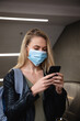 © Wavebreak Media - Caucasian woman on the go wearing a covid19 coronavirus mask and using her phone