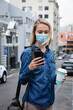 © Wavebreak Media - Caucasian woman wearing a covid19 coronavirus mask outside and using her phone