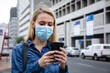 © Wavebreak Media - Caucasian woman wearing a covid19 coronavirus mask outside and using her phone