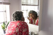 © Wavebreak Media - A senior African American woman looking at her reflexion in the mirror and taking care of herself