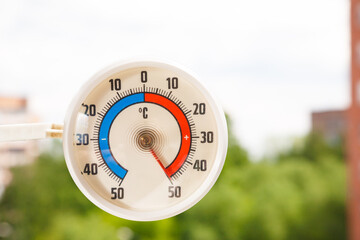 round street outdoor thermometer with arrow shows extreamly high temperature on hot sunny summer day
