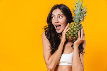 Poster - Image of excited brunette woman holding pineapple and looking aside