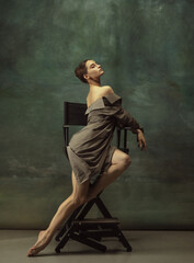 Wall Mural - Beautiful portrait, elegance. Graceful classic ballerina dancing, posing isolated on dark studio background. Stylish trench coat. Grace, movement, action and motion concept. Looks weightless, flexible