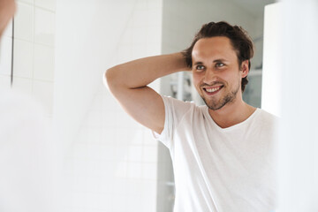 Wall Mural - Attractive young man standing in front of the bathroom mirror