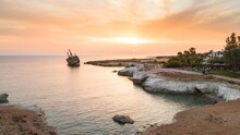 Aerial Bird’s Eye View Of The Abandoned Ship Wreck EDRO III In Pegeia, Paphos, Cyprus From Above At Sunset. Rusty Shipwreck Stranded On Peyia Rocks At Sea Caves, Coral Bay In Pafos, Standing On Coast.
