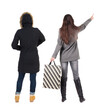 © ghoststone - back view of two women with shopping bags in winter jacket.